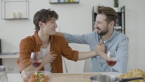Two men confessing love, holding hands and talking sincerely, romantic dinner