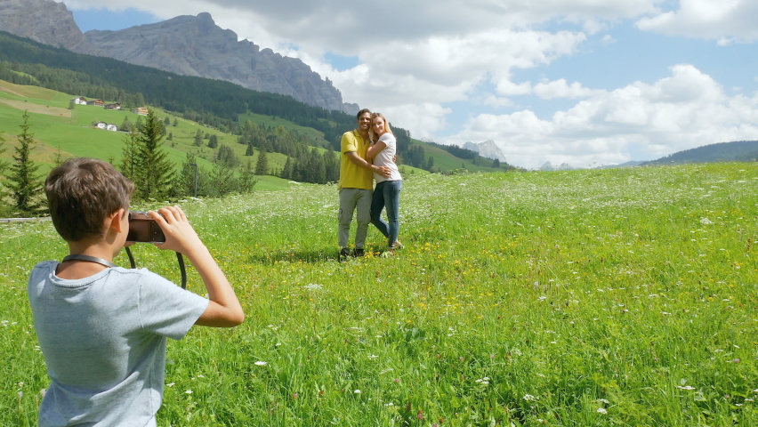 Boy (8-9) photographing parenin Alpine meadow