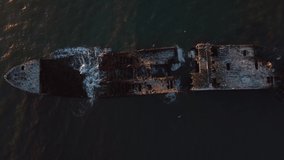Sunken Ship off the Coast with Birds and Wildlife. Drone video of shipwreck in the ocean with animals flying around. Half sunken boat aerial footage.