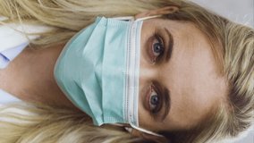 A Vertical Video, 9.16 Portrait Of A Relieved White Female Medical Doctor Removing Her Face Mask After Achieving Full Immunity With The Covid-19, SARS-CoV-2 Vaccine. Wearing Safety Gloves And Mask