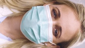 A Vertical Video, 9.16 Portrait Of A Relieved White Female Medical Doctor Removing Her Face Mask After Achieving Full Immunity With The Covid-19, SARS-CoV-2 Vaccine. Wearing Safety Gloves And Mask