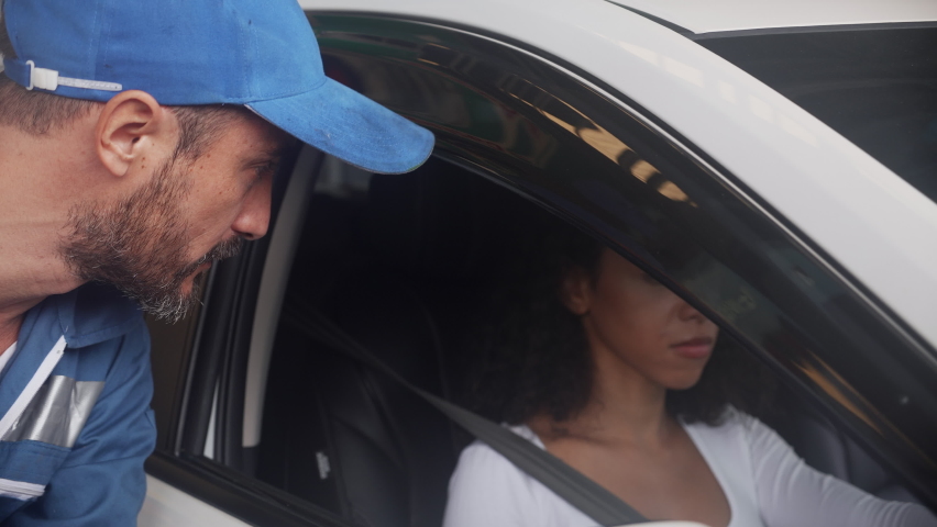 Customer young woman talking with mechanic man about problems of engine car and giving key car in the garage, technician examining vehicle and repairing of client, two people, auto service.