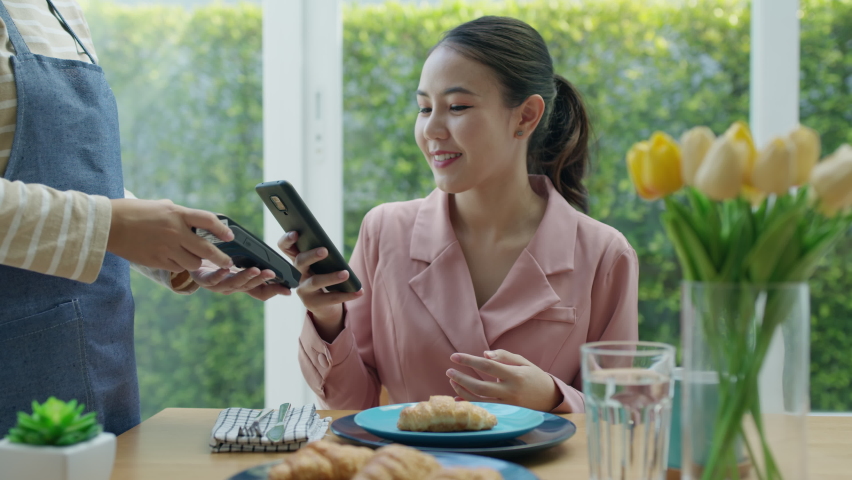 Asia young smile happy woman people in small sme coffee shop store use tapping cashless wifi qr code nfc scan app smart pos device reader sale in food drink order in café urban city life contactless. | Shutterstock HD Video #1073807621