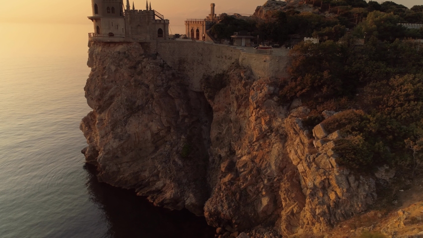 Crimea swallow's nest famous landmark Russia Gaspra. Aerial around cinematic Neo-Gothic castle fortress on edge of epic cliff above sea at orange sunrise. Best Travel explore. Fairy tale Royalty-Free Stock Footage #1073809460