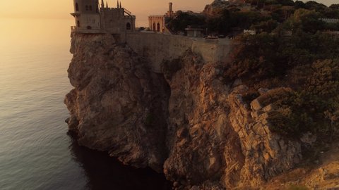 Crimea swallow's nest famous landmark Russia Gaspra. Aerial around cinematic Neo-Gothic castle fortress on edge of epic cliff above sea at orange sunrise. Best Travel explore. Fairy tale