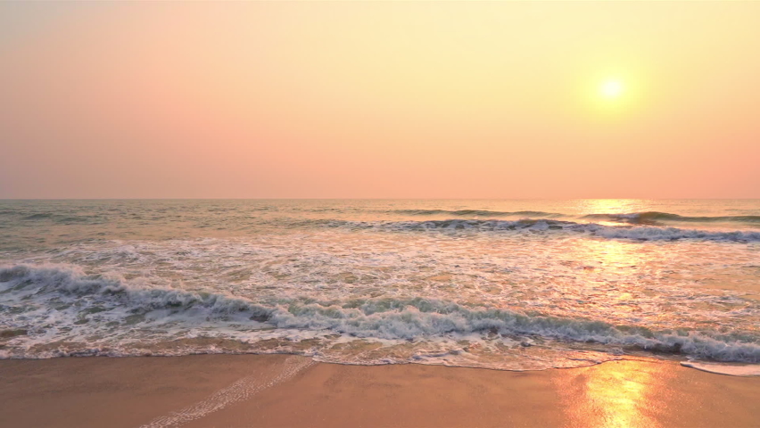 Small ocean sea waves on a sandy beach during sunset. Background landscape picture of dusk or dawn at the Atlantic ocean beach with small waves at low tide