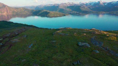 Aerial view of two hikers walking down towards the Skaland village, on the Husfjellet trail, in Senja, Norway - tracking, drone shot