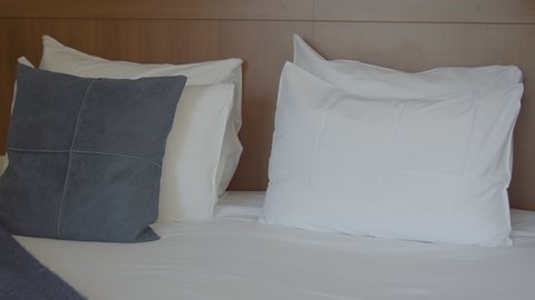 Decorative pillow being placed on hotel room bed