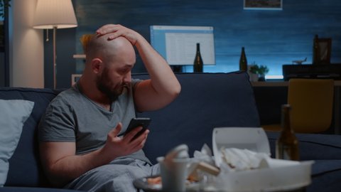 Shocked, worried man by warning notification for unpaid bank bills received on smartphone putting hands on head crying. Disappointed, frustrated, annoyed desperate male reading digital eviction notice