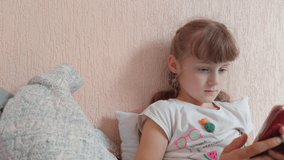 Little girl with phone blinking eyes on the bed home interior indoors