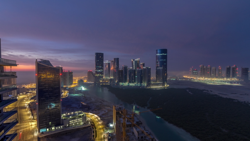 Skyscrapers on Al Reem in Abu Dhabi timelapse during sunrise from above. Aerial citiscape from Al Reem Island at morning with fog. Sun reflected on glass surface | Shutterstock HD Video #1073830229