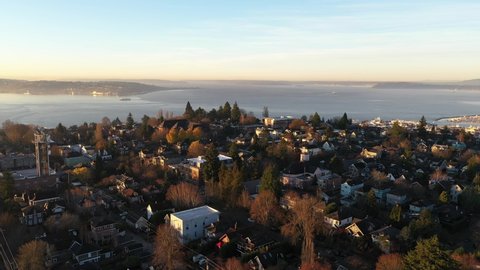 Sunrise aerial - drone shot of West Queen Anne, Queen Anne, Lower Queen Anne, Interbay, Alki, upscale, affluent neighborhoods uptown by Puget Sound, in Seattle, Washington