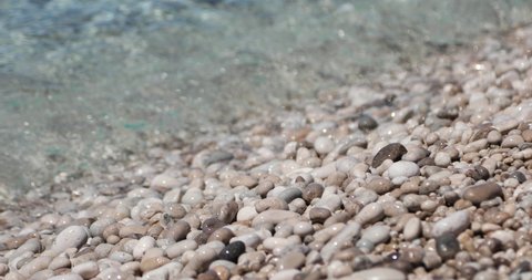 Clean sea water of Mediterranean Sea rolling in sunshine to the pebbles beach