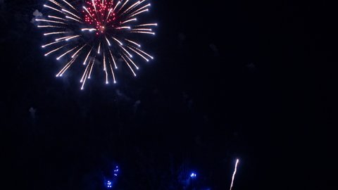 Long thin lines of light burst into explosions of colorful fireworks. 