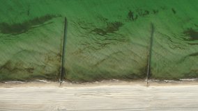 vertical view of an empty sandy beach with breakwater while overflying the shoreline 