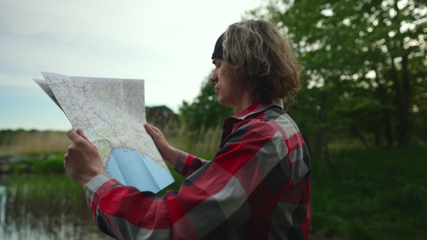 Male tourist with map by the lake.