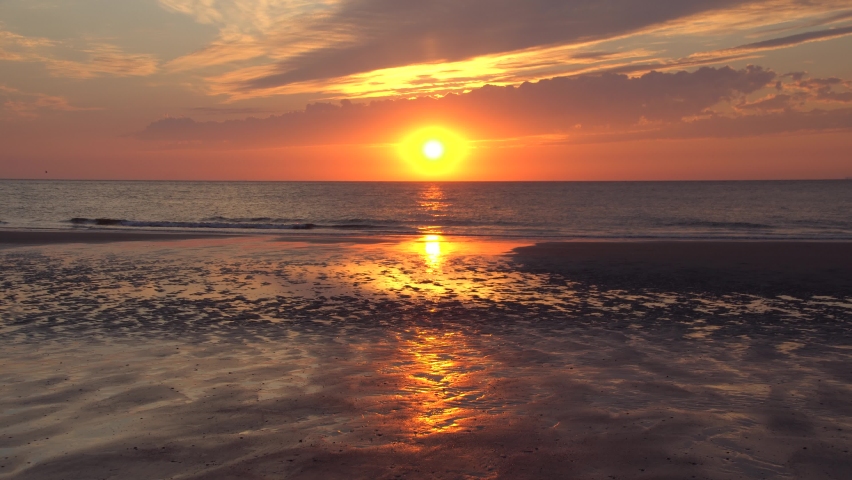 Yellow Sun And Dark Water Surface. Beautiful Red Sunset On The Populated East Frisian Island Of The North Sea Coast Of Germany. Summer Nature Of Norderney.