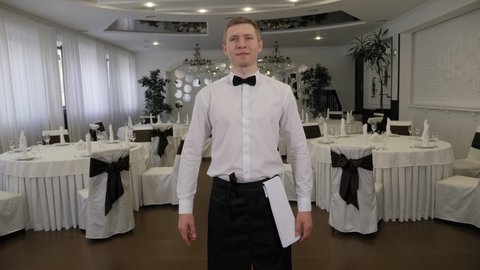 Portrait of a waiter in a restaurant before work, he straightens his bow tie.