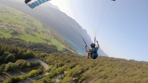 Man flying extreme paraglider in swiss alps, wide angle lens. Adventure freedom concept.