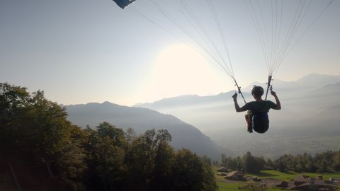 Man flying extreme paraglider in swiss alps, freedom concept.
