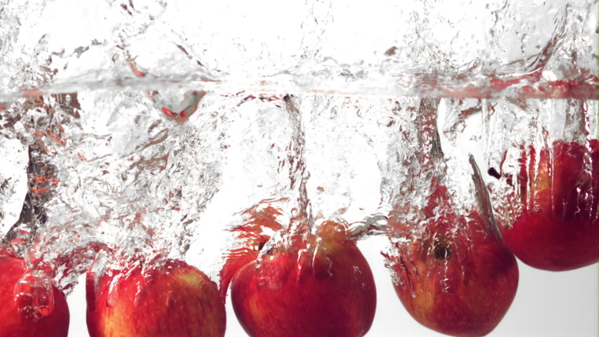 Super slow motion red apples fall into the water with splashes. On a white background.Filmed on a high-speed camera at 1000 fps. High quality FullHD footage