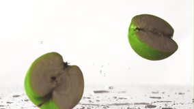 The super slow motion green apple falls on the table and splits into half. On a white background. Filmed on a high-speed camera at 1000 fps. High quality FullHD footage - Powered by Shutterstock - Get 15% off with code: PIKWIZARD15