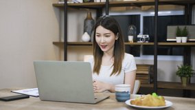 Asian woman using laptop making video call for distant meeting or online support working from home while coronavirus pandemic