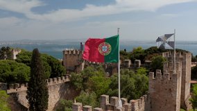 Close up aerial view of Portugal and Lisbon flag waving in the wind on the top of Castelo de S Jorge Lisbon castle on top of the hill overlooking the sea - Powered by Shutterstock - Get 15% off with code: PIKWIZARD15