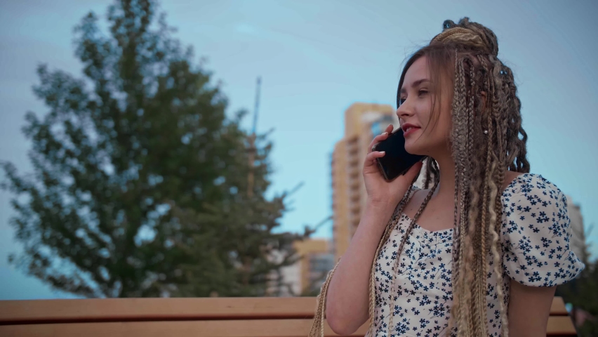 Young and beautiful girl talking on a smartphone in the street