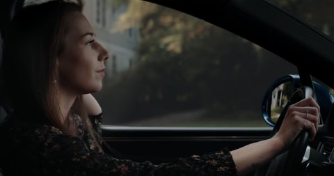 CU Portrait of attractive Caucasian female texting while driving her car through neighborhood. Shot with 2x anamorphic lens