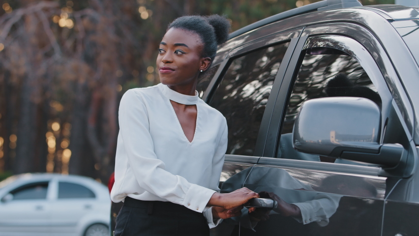 Smiling african american girl happy ethnic black woman driver passenger stands on street outdoors opens car door get sitting into taxi service in grey automobile, trip travel driving on road concept Royalty-Free Stock Footage #1073862293