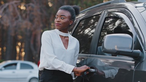 Smiling african american girl happy ethnic black woman driver passenger stands on street outdoors opens car door get sitting into taxi service in grey automobile, trip travel driving on road concept