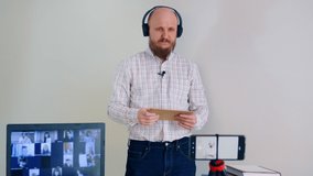 A bald man with a beard wearing headphones and a microphone opens an envelope with a gift in front of his online viewers. Takes a pen out of the envelope and is surprised.