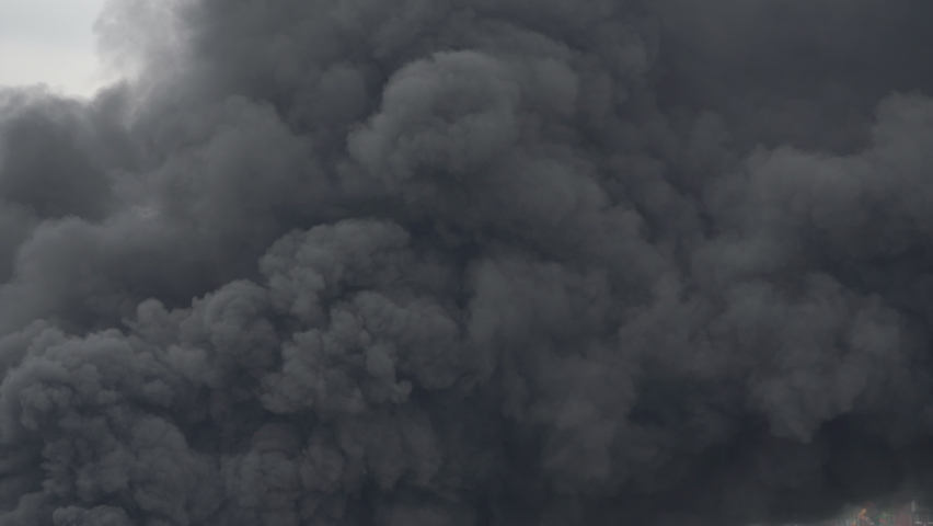 Puffs of dramatic black clouds of toxic smoke moving across sky from violent fire. Concept natural catastrophe, industrial ecological disaster, fire extinguishing. Background black billowing smoke sky