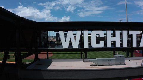 Wichita, Kansas USA - May 28th 2021: Drone panning shot of Riverfront baseball stadium nameplate in downtown Wichita Kansas 4k