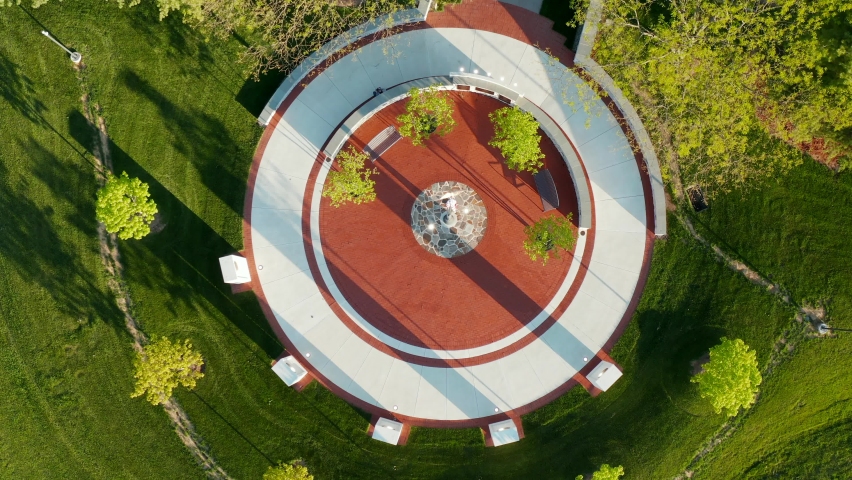 Descending aerial. Round circle with memorial exhibit and American flag honoring veterans who served in USA war.