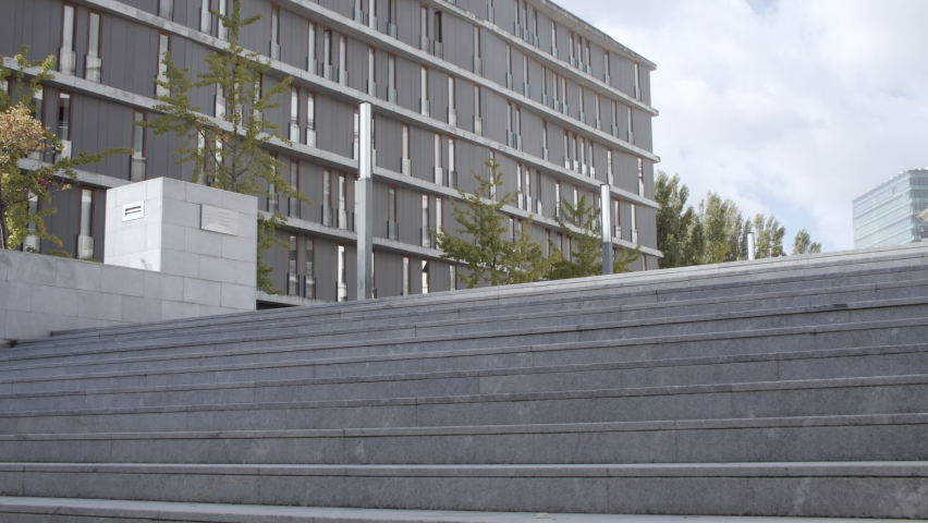 Young brunette businesswoman going upstairs. Content female employee or entrepreneur in office suit ascending staircase outdoors. Static camera. Long shot. Business, work and occupation concept