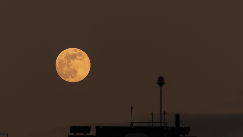 Full moon over the city time lapse. Moon raising over antenna on the roof