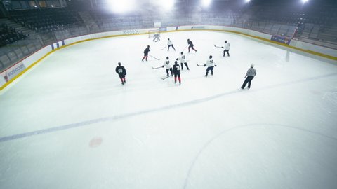 Aerial Ice Hockey Rink Arena Game Start: Two Players Brutal Face off, Referee Drops the Puck, Leading with Masterful Dribble Player Scores Goal when Goalie Misses the Puck. Drone High Angle Shot