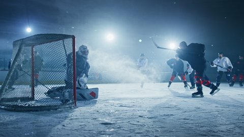 Ice Hockey Rink Arena: Best Goalkeeper Against Professional Forward Player who Breaks Defense, Shooting Puck with Stick and Scoring Beautiful GOAL. Cinematic Fast Slow Motion Wide Shot