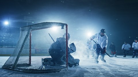 Ice Hockey Rink Arena: Goalie against Forward Player who Does Slapshot, Shots Puck with Stick and Scores Goal. Forwarder againstGoaltender.Team Celebrates. Cinematic Slow Motion Behind Goals Wide Shot