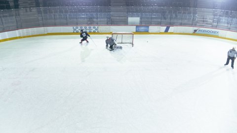 Ice Hockey Rink Arena: Professional Forward Player Masterfully Dribbles, Breaks Defense, Hitting Puck with Stick but Goalkeeper Successfully Catches it. Athletes Play. High Angle Aerial Drone Shot
