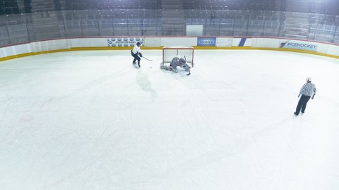 Aerial Drone Ice Hockey Rink Arena: Professional Forward Player Masterfully Dribbles, Breaks Defense, Shooting Puck with Stick Scores Goal, Goalie Missed it. Leading Team to Victory. High Angle View