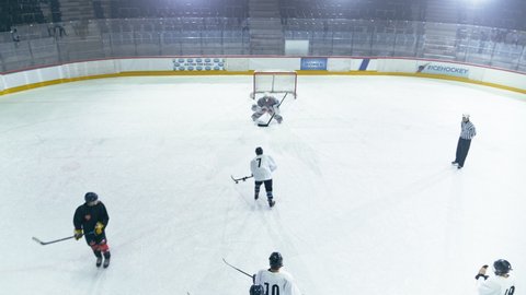 Aerial Drone Ice Hockey Rink Arena: Professional Forward Player Masterfully Dribbles, Breaks Defense, Hitting Puck with Stick Scores Goal, Goalie Missed it. Overtime Shots. High Angle Static View