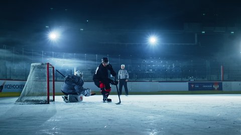 Ice Hockey Rink Arena: Professional Forward Player Masterfully Dribbles, Hitting Puck with Stick Scores Goal, Goalie Missed it. Forwarder againstGoalkeeper One on One. Cinematic Slow Motion Wide Shot