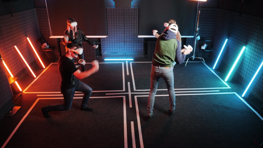 Group of happy joyful people in VR headset glasses gaming together. Virtual reality happiness simulation studio. Oculus game gadget helmets fun. Person joy. Gamer groups in neon red blue background. - Powered by Shutterstock - Get 15% off with code: PIKWIZARD15