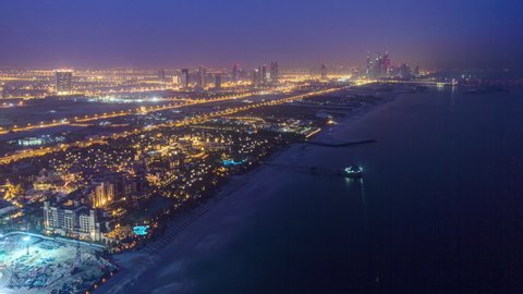Skyline view of Dubai night to day transition timelapse showing Dubai marina skyscrapers and beach in Dubai, UAE. Aerial panorama from helipad
