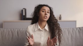 Mental help. Psychologist pov portrait of young emotional annoyed woman talking to camera, complaining about life problems, sitting on sofa, slow motion