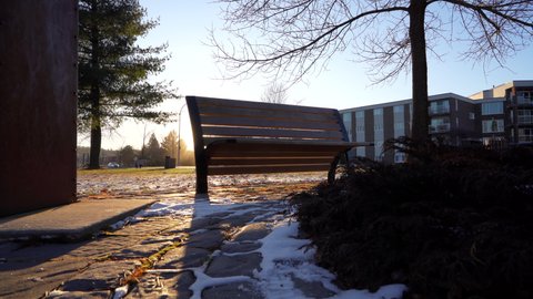 Pan shot of a benchpark in winter by sunset
