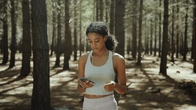 Mixed race female teen running in forest listening to music with earphones